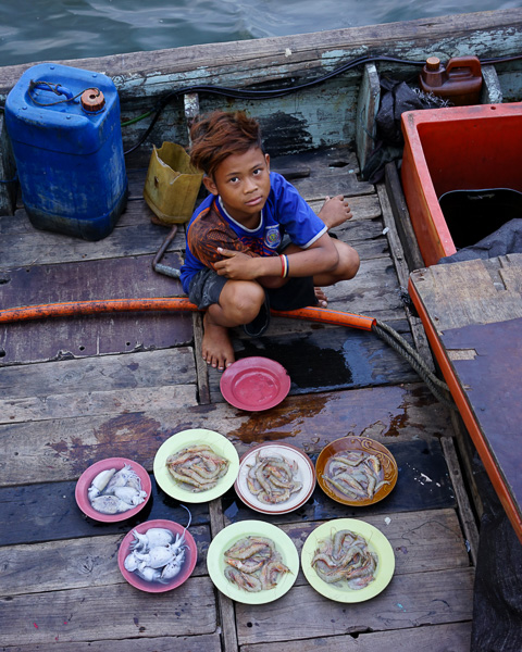 Anak nelayan berusaha menjual udang dan cumi kepada pengunjung pantai Ancol. ISO 400m f/3.5, 1/50 detik, 35mm